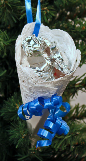 Easy Christmas Crafts Paper Doily Cone Ornament finished with blue ribbon hanging on tree